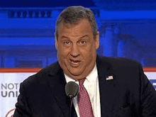 a man in a suit and tie is giving a speech in front of a microphone .