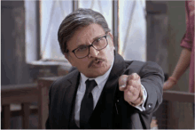 a man with glasses and a mustache is pointing his finger