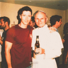 a man in a maroon shirt is posing for a picture with a man in a white robe holding a bottle of beer