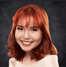 a woman with red hair and bangs is smiling for the camera