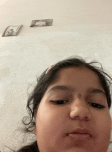 a young girl is making a funny face in front of a white wall