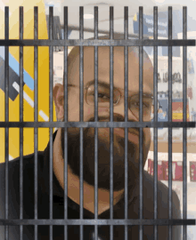 a man with glasses and a beard is behind bars in a store