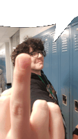 a person giving a middle finger in front of a row of blue lockers