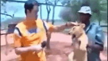 a man is holding a lion cub in his arms while another man looks on .