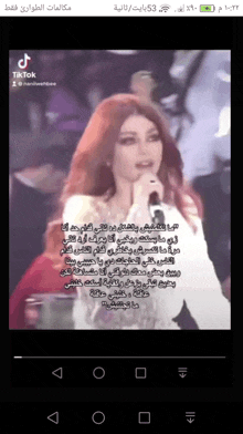 a woman singing into a microphone with arabic writing on the screen