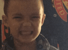 a young boy is making a face in front of a united shirt