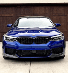 a blue bmw parked in front of a wooden garage door