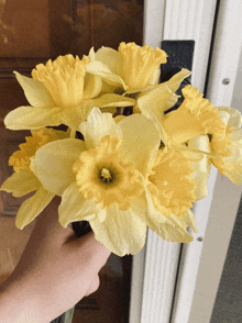 a person is holding a bouquet of yellow flowers in front of a door