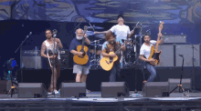 a group of men are playing guitars on a stage in front of a sign that says ' music '