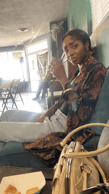 a woman sitting in a chair holding a cup of coffee and a purse