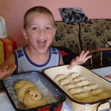 a young boy is sitting at a table with a pan of food .