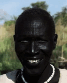 a man with black skin is smiling and wearing a necklace of beads