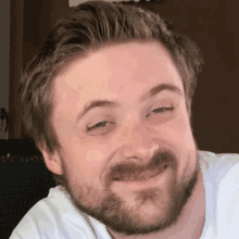 a man with a beard wearing a white shirt smiles for the camera