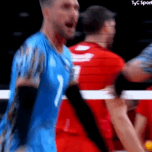 a man in a blue jersey with the number 7 on it is playing volleyball