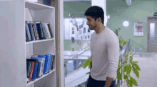 a man standing in front of a book shelf with a book titled " a brief history of the world "