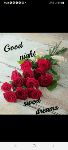 a bunch of red roses on a wooden table with the words good night sweet dreams written on it