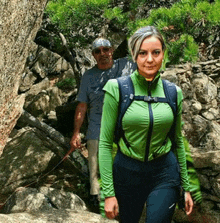 a woman in a green shirt is walking with a man in a blue shirt behind her