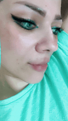 a close up of a woman 's face with a green shirt on