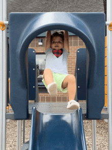 a little girl hanging upside down on a slide at a playground