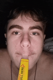 a close up of a man holding a yellow stick in his mouth .