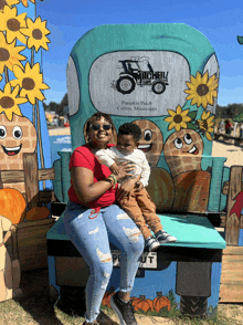 a woman is holding a child in front of a sign that says mitchell 's