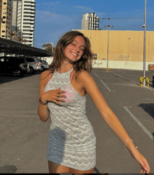 a woman in a dress stands in a parking lot