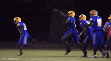 a group of football players are running on a field with the words shot by blake visible in the corner