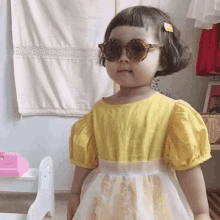 a little girl wearing sunglasses and a yellow dress .