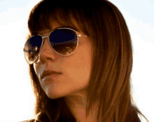 a woman wearing sunglasses has a reflection of a city in her sunglasses