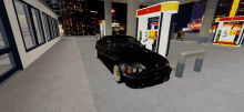 a black car is parked in front of a gas pump that says ' 1 ' on it