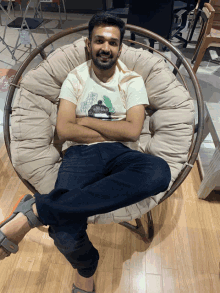 a man sitting in a round chair with his arms crossed