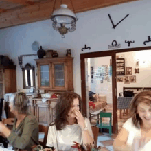 a group of women are sitting at a table in a room with a clock on the wall that says ' v '