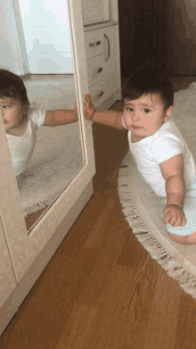 a baby looks at his reflection in the mirror