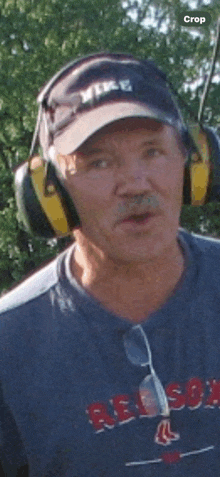 a man wearing a red sox shirt and ear muffs