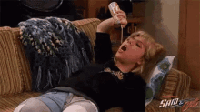 a woman is laying on a couch holding a bottle of milk and drinking it .