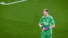 a soccer player in a green jersey is standing next to another player in a red jersey on a soccer field .