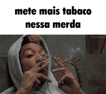 a man in a hoodie smoking a cigarette with the words mete mais tabaco nessa merda above him