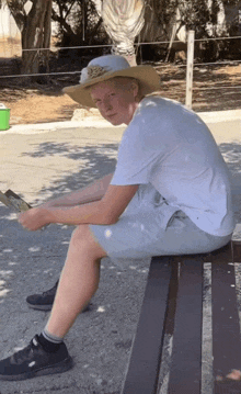 a man in a cowboy hat is sitting on a bench