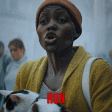 a woman in a yellow sweater is holding a cat and the word run is in red