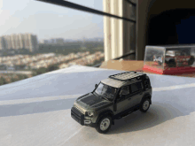 a green toy land rover defender sits on a table