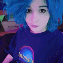 a girl with blue hair is wearing a t-shirt that says inims