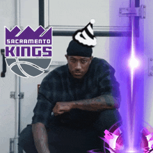 a man wearing a party hat is kneeling in front of a sign for the sacramento kings