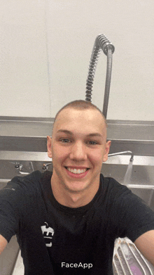 a man in a black shirt is smiling in front of a faucet with faceapp written on the bottom