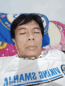 a man laying on a bed with his eyes closed and wearing a shirt that says ' nama ' on it