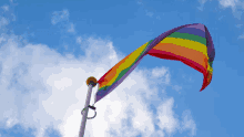 a rainbow flag is flying in the blue sky