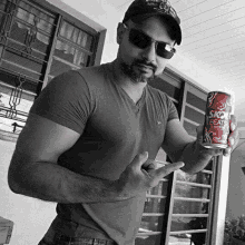 a man wearing sunglasses and a hat is holding a can of skol beer in his hand .