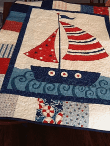 a red white and blue sailboat quilt is on a wooden table