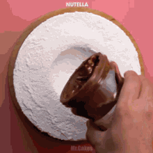 a person is pouring nutella onto a cake