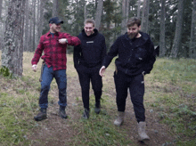 three men are walking in the woods and one of them has a black hoodie that says abercrombie on it