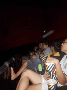 a group of people are sitting in a theater watching a movie with their feet up